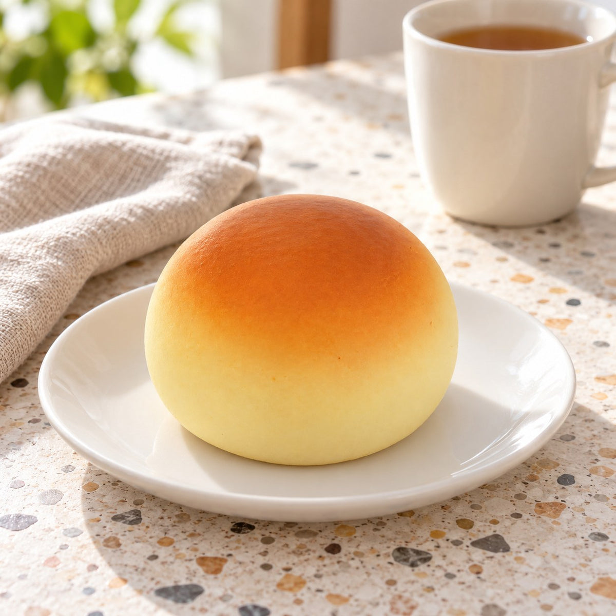 Steamed bun squishy (golden), on a plate on a breakfast table