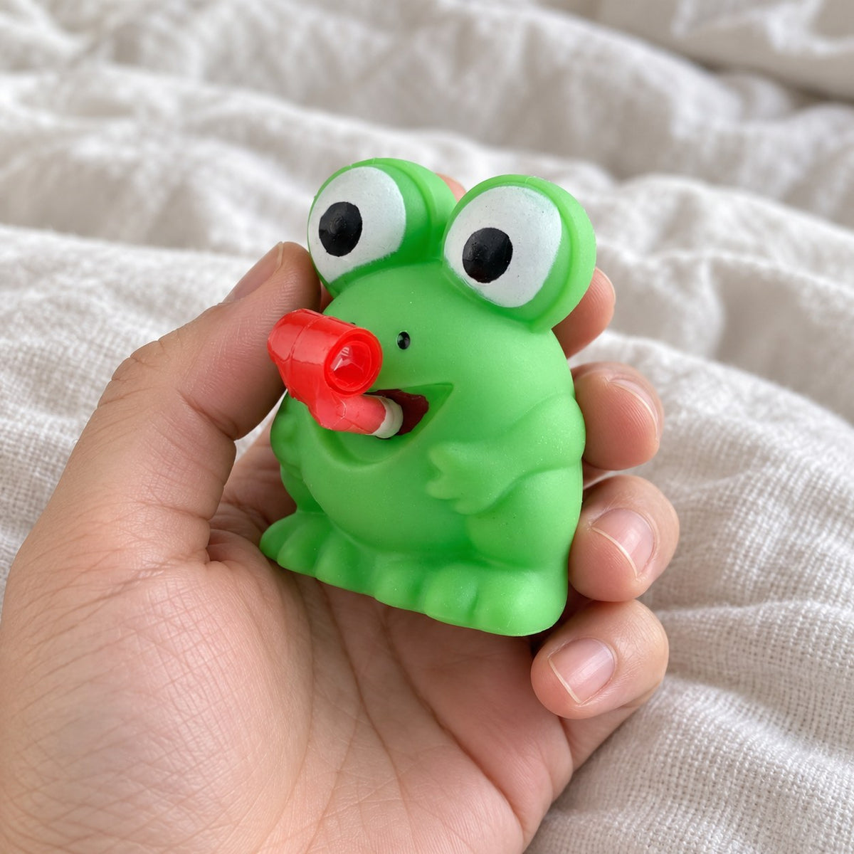 Squishy groda eller dino som räcker ut tungan (Groda, slumpvis färg), hålls mot kameran ur eget perspektiv