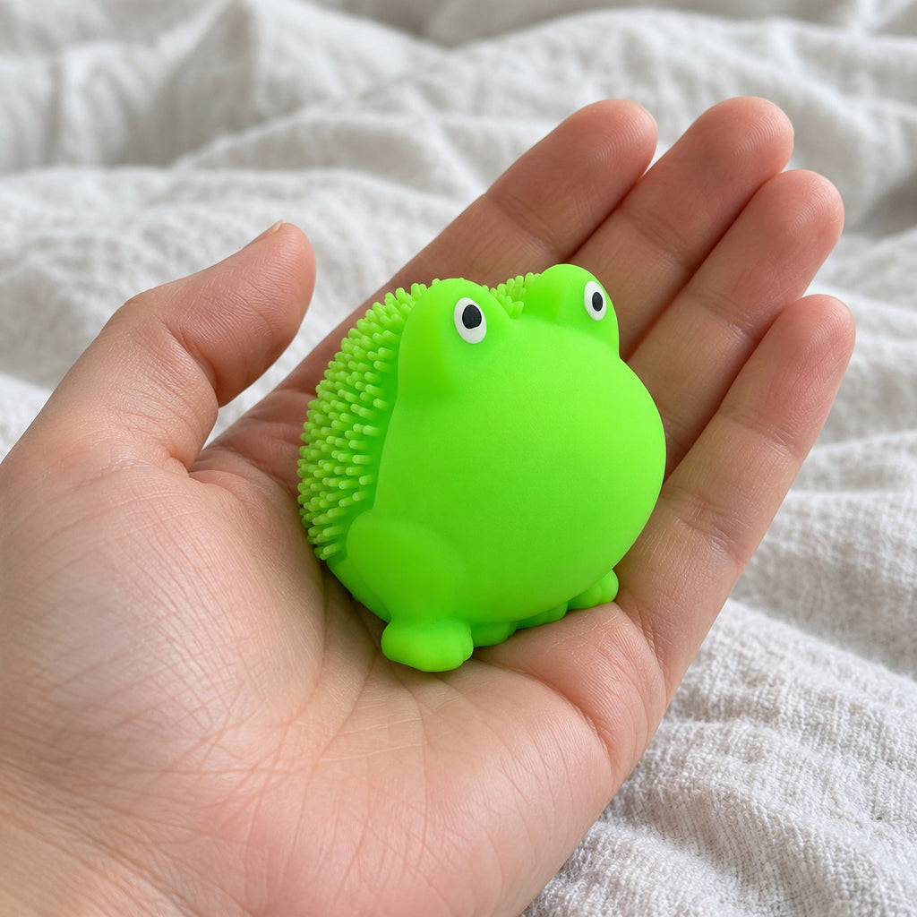 Squishy žabka s měkkými bodlinkami, TPR, 5 cm, držený směrem k fotoaparátu z pohledu první osoby