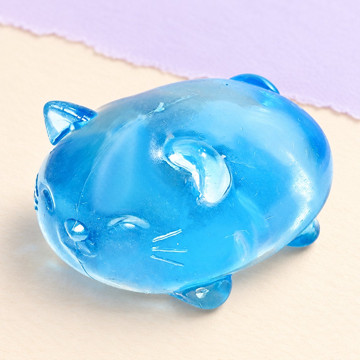 Blauwe gelei kat squishy, doorzichtig, op pastelkleurig papier