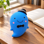 Ghost squishy (blue), on a desk with a notebook and pencil