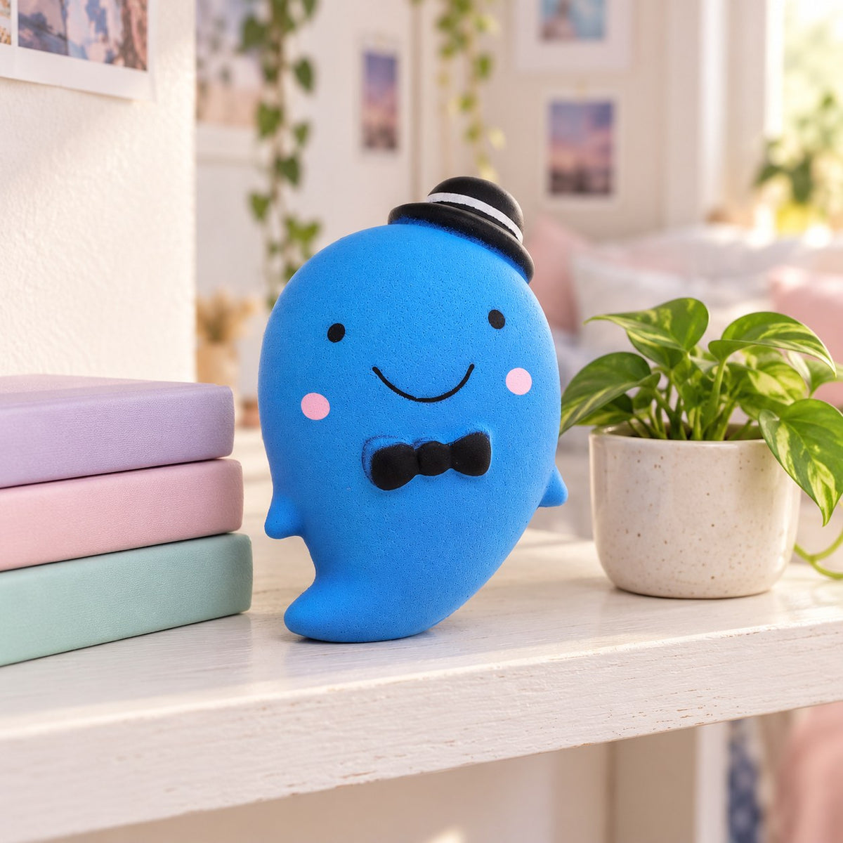 Slow Rising Ghost Squishy, 14.5 cm (blue), on a shelf with books and a plant as room decor