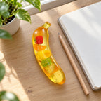 Giant Banana Squishy, Jumbo Slow Rising, on a desk with a notebook and pencil
