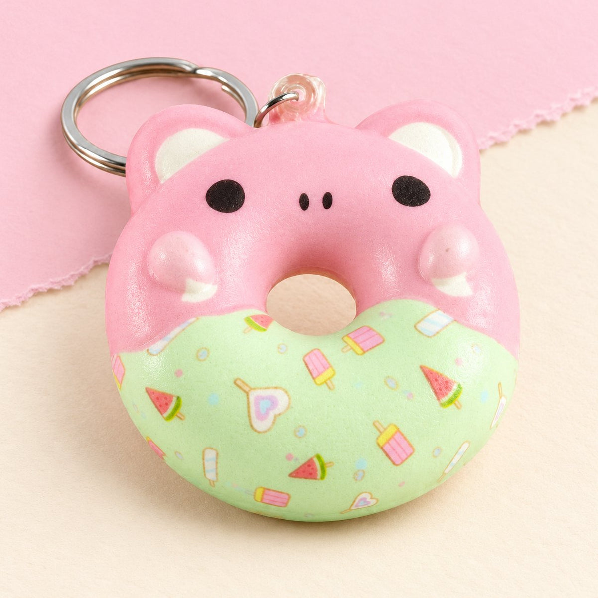 Gniotek brelok donut z buzią zwierzaka, slow rising, na pastelowym papierze
