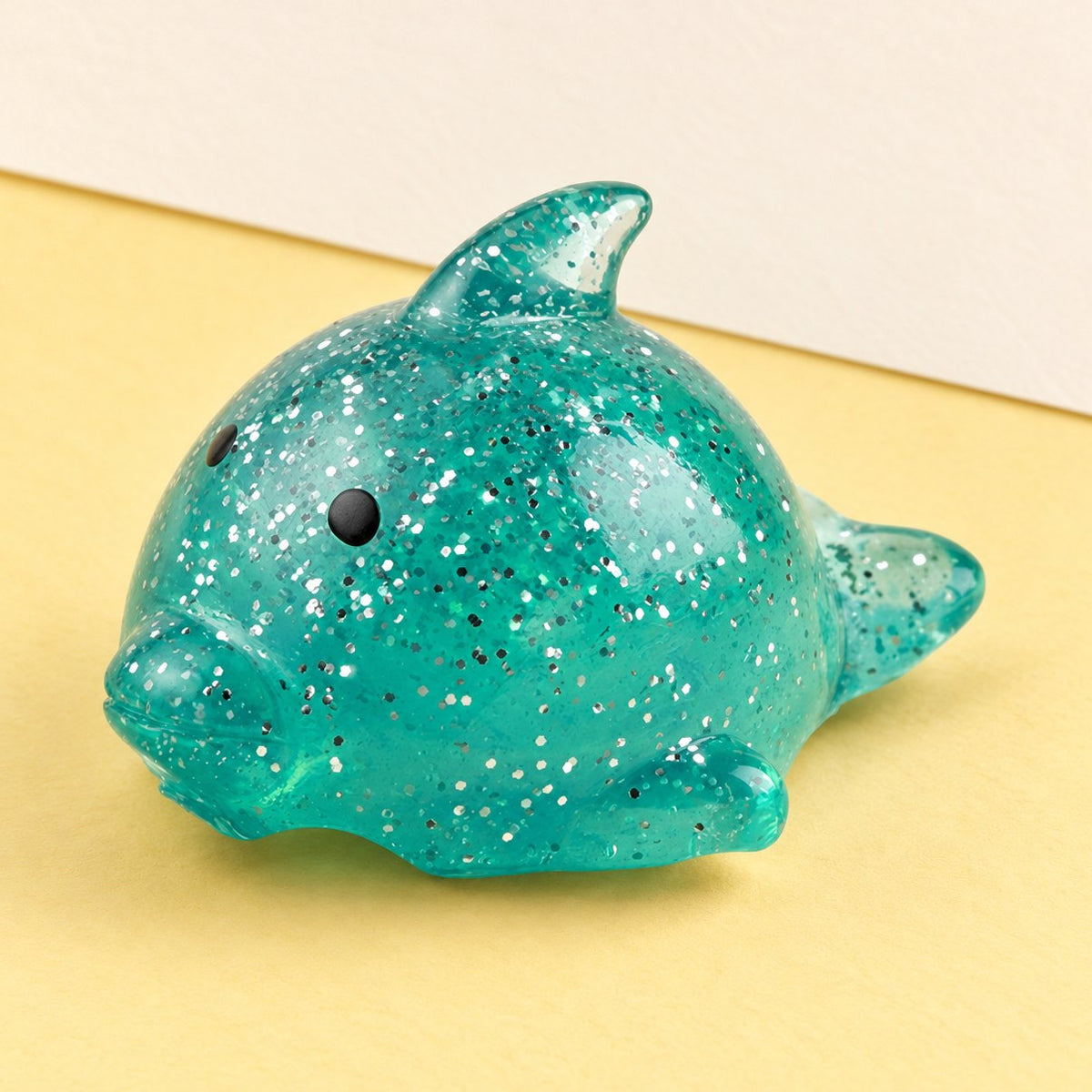 Duży gniotek delfin mochi z brokatem na pastelowym papierze