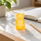 Gummy Bear Squishy, Slow Rising (orange), on a desk with a notebook and pencil