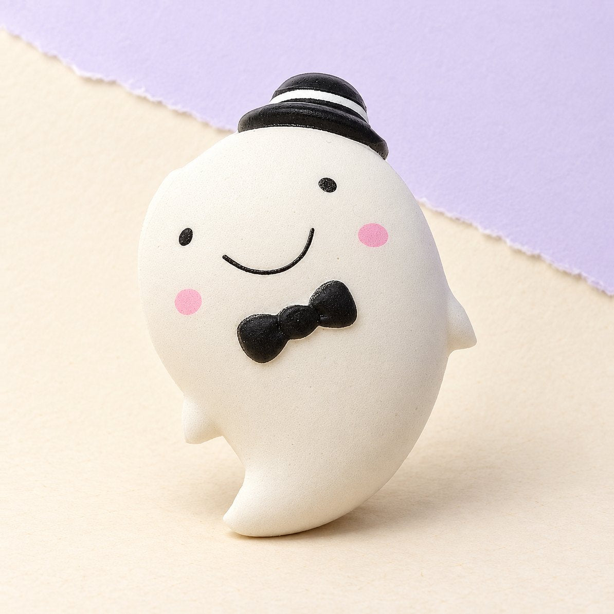 Hvid halloween-squishy, slow rising, 14,5 cm, produktfoto på pastelfarvet papir