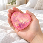 Glitter Heart Squishy, Maltose Style 6.7 cm (pink), held in a hand to show the real size