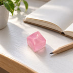 Mini Jelly Ice Cube Squishy, 2.5 cm (pink), on a desk with a notebook and pencil