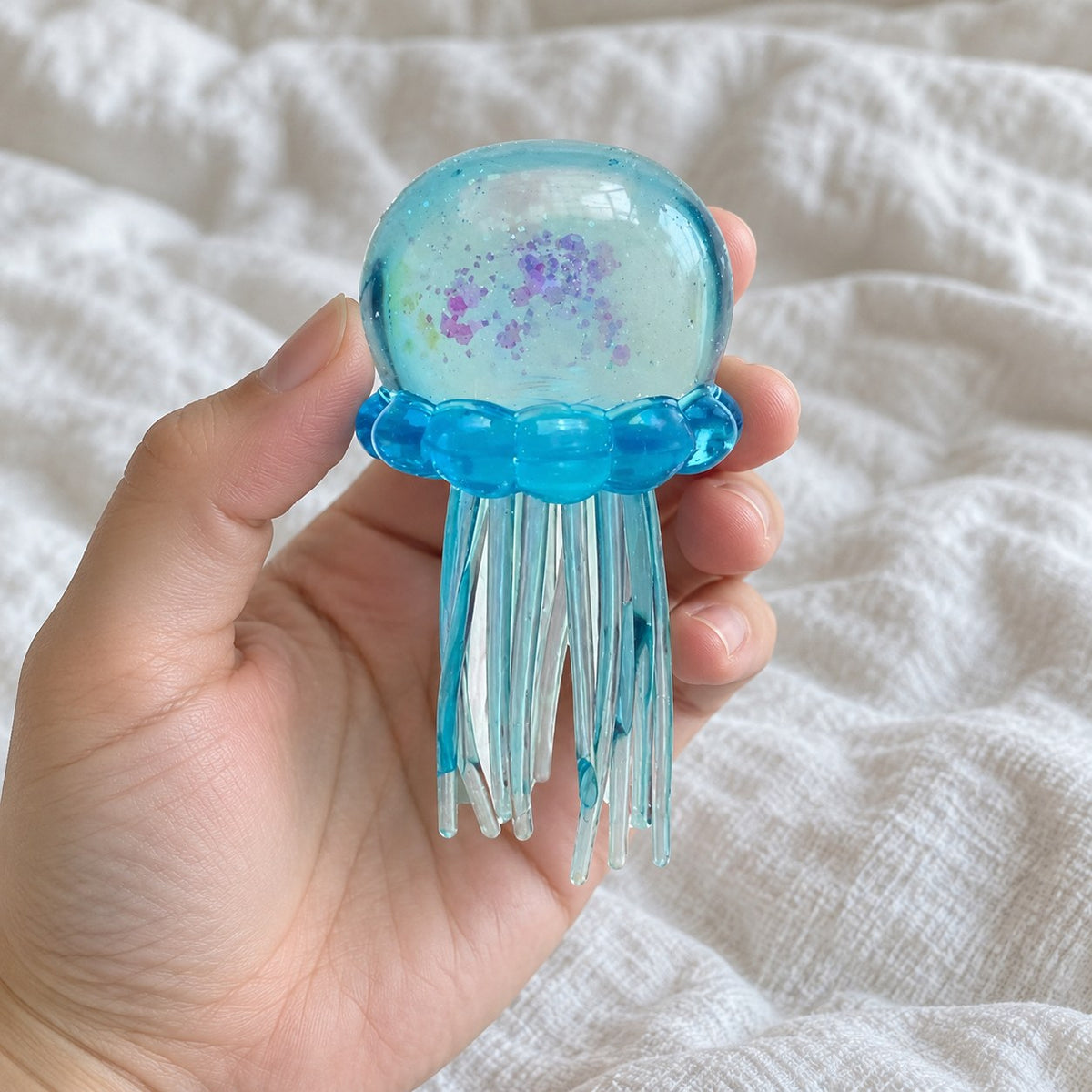 Jellyfish squishy glitter (blue), held toward the camera, first-person view