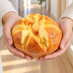 Squishy kæmpebrød, rundt brød 14,5 cm, holdt med begge hænder, så man ser hvor stor den er