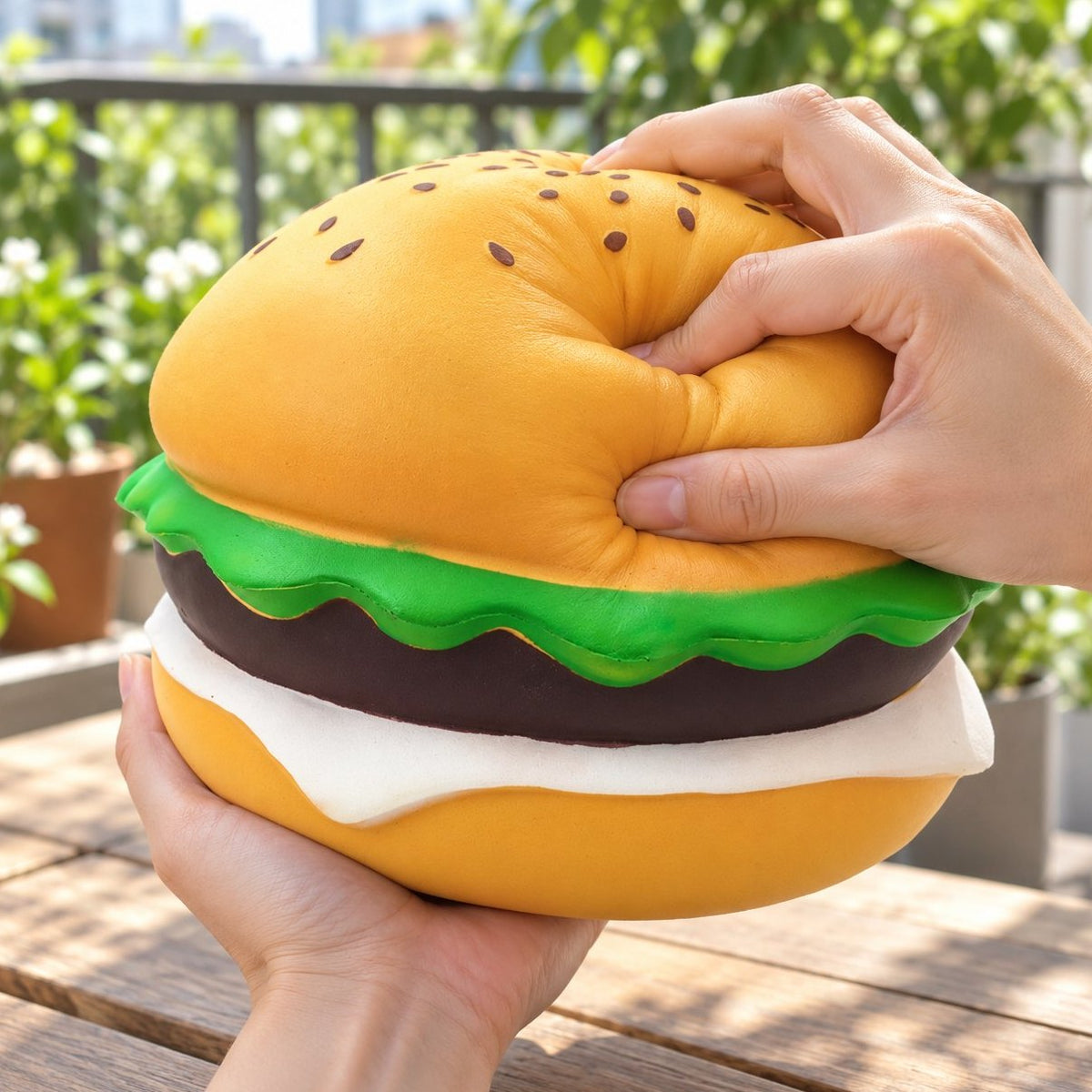 Reuzenburger met sesam van 24 cm: jumbo burger squishy wordt in de hand ingedrukt
