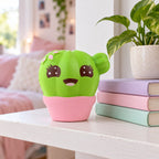 Cactus squishy jumbo, on a shelf with books and a plant as room decor