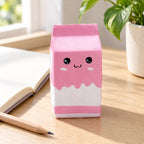 Jumbo Milk Carton Squishy, Slow Rising (pink), on a desk with a notebook and pencil