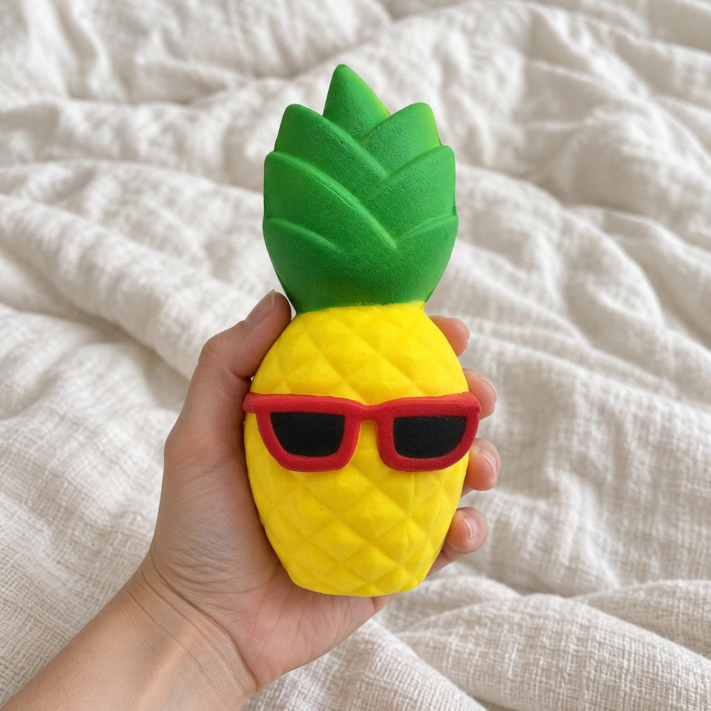 Jumbo Pineapple Squishy with Sunglasses, held toward the camera, first-person view