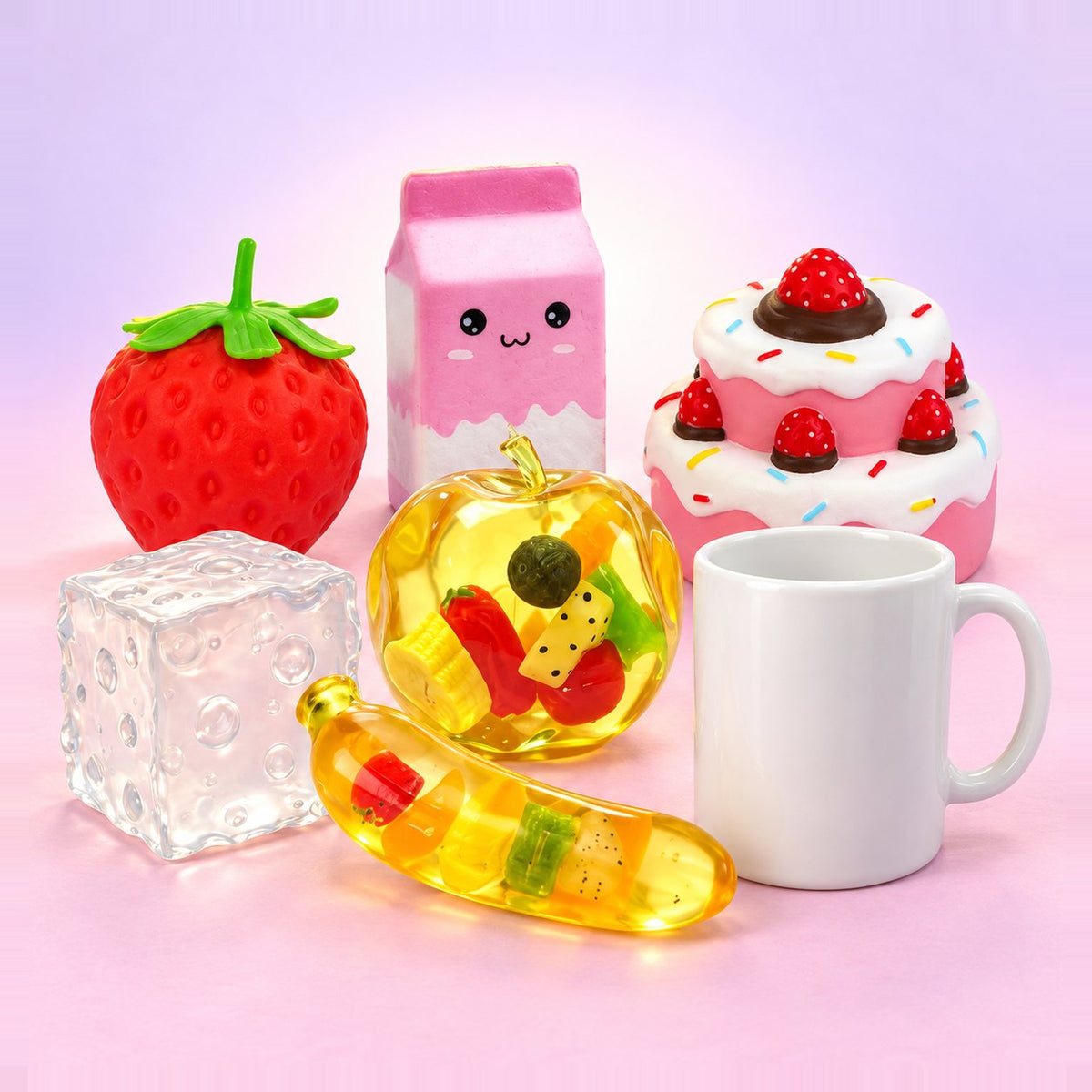 Kæmpe boks squishy: 6 store squishies fra banan til jordbærkage, ved siden af et hvidt krus