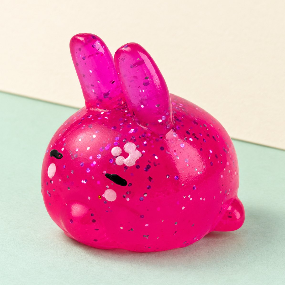 Kanin-squishy med glimmer, produktfoto på pastelfarvet papir