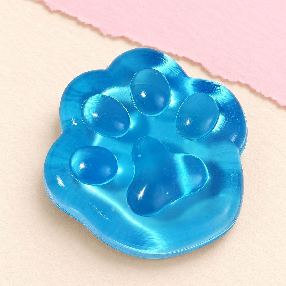 Kattenpootje squishy van gelei, mini van 4 cm in blauw, op pastelkleurig papier