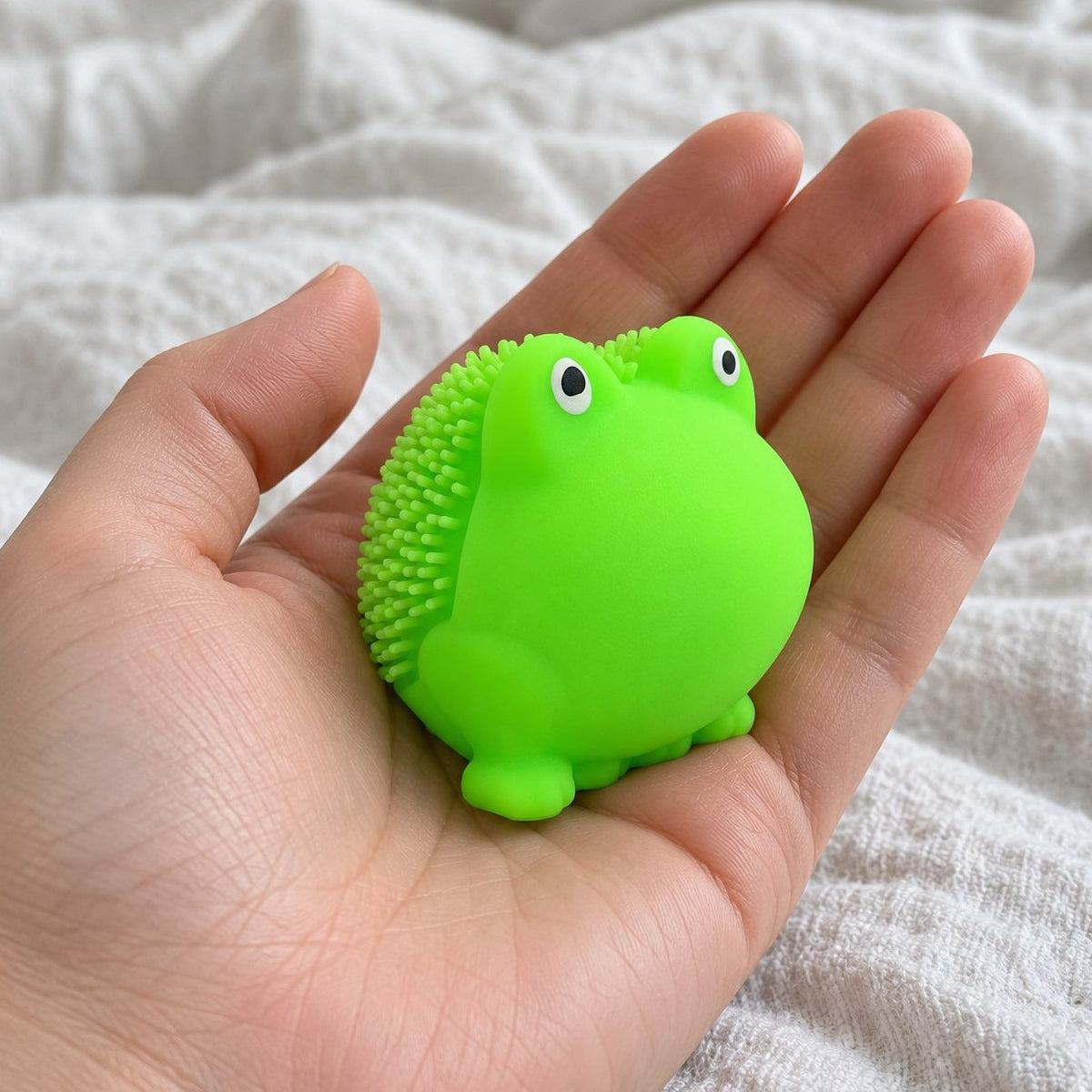 Vanuit eigen perspectief: kikker squishy met zachte stekels naar de camera gehouden