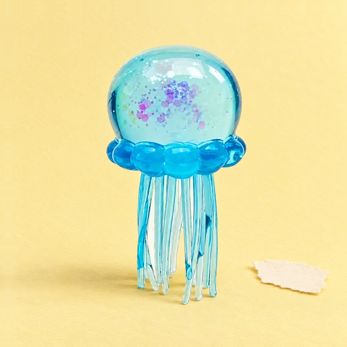 Kwal squishy met glitter in blauw, zacht TPR, op pastelkleurig papier