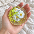 Maltose ball squishy (Spring Daisies), held toward the camera, first-person view
