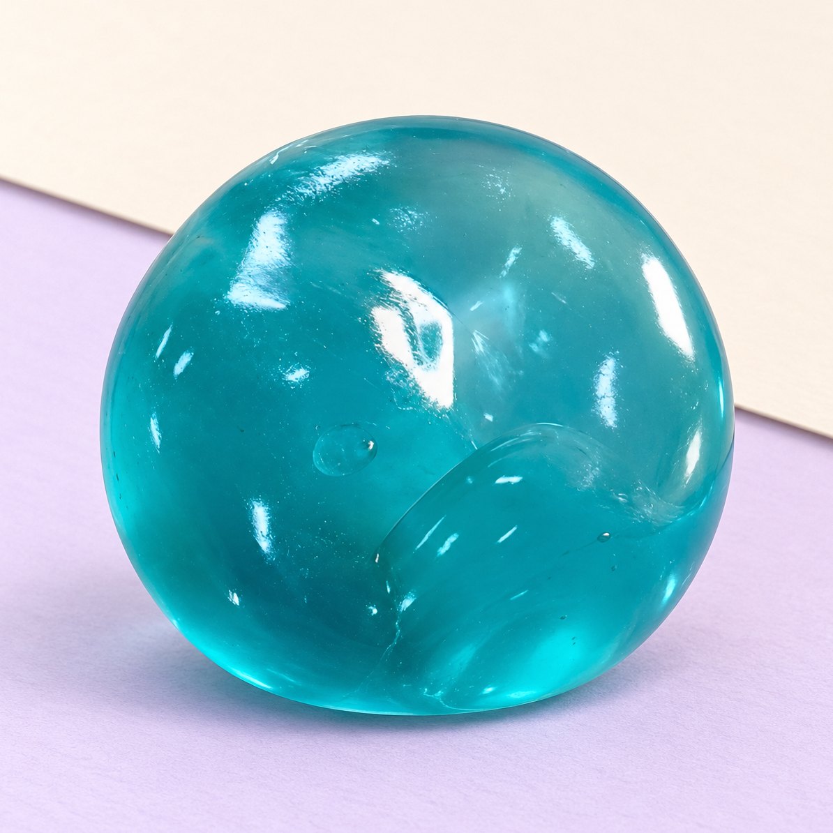 Havblå maltosebold-squishy af gelé, slow rising, produktfoto på pastelfarvet papir
