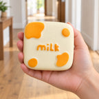 Milk squishy kawaii, held in a hand to show the real size