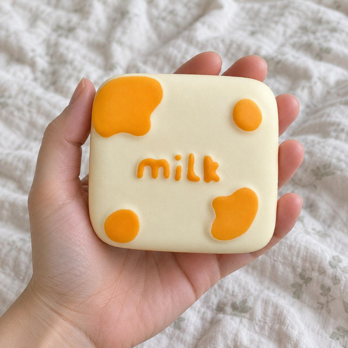 Milk block squishy, held toward the camera, first-person view