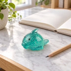 Big Mochi Squishy Dolphin with Glitter, on a desk with a notebook and pencil