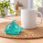 Big Mochi Squishy Dolphin with Glitter, next to a coffee mug for size comparison
