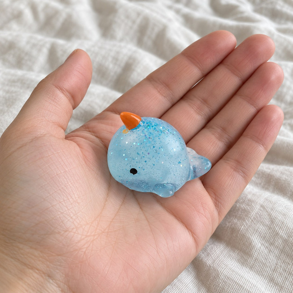 Narwhal squishy mochi, held toward the camera, first-person view