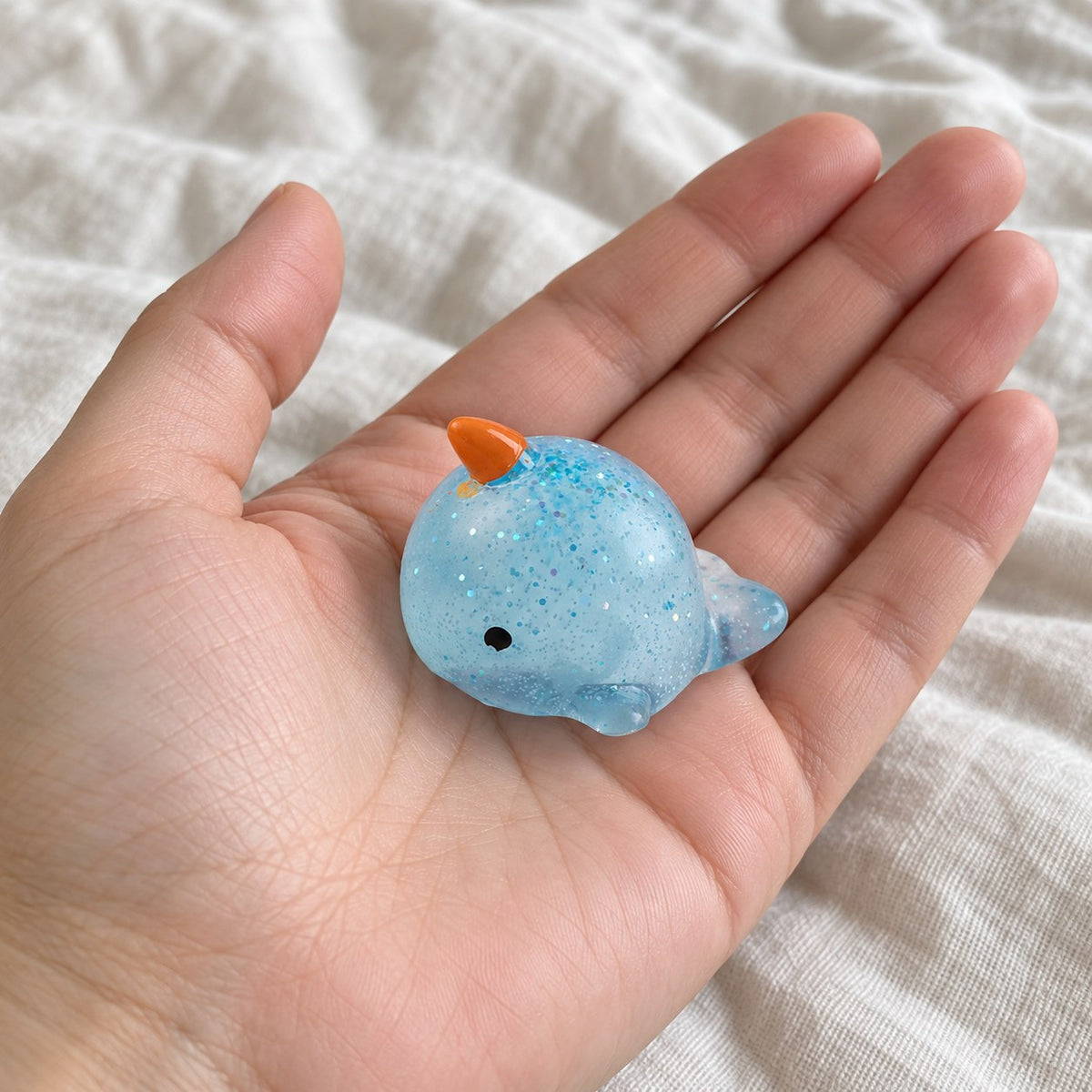 Narwhal squishy mochi, held toward the camera, first-person view