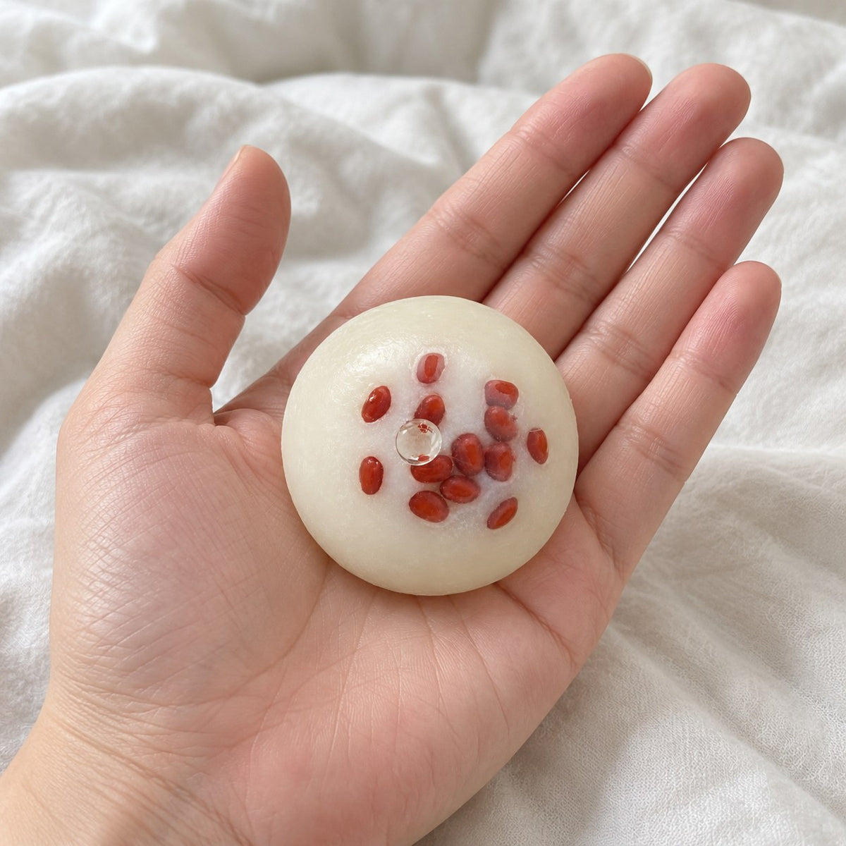 Red bean mochi squishy, held toward the camera, first-person view