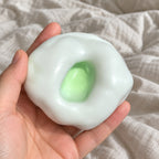 Rice cake squishy (green), held toward the camera, first-person view