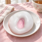 Mochi Squishy Rice Cake, Stretchy Ice Skin (pink), on a plate on a breakfast table