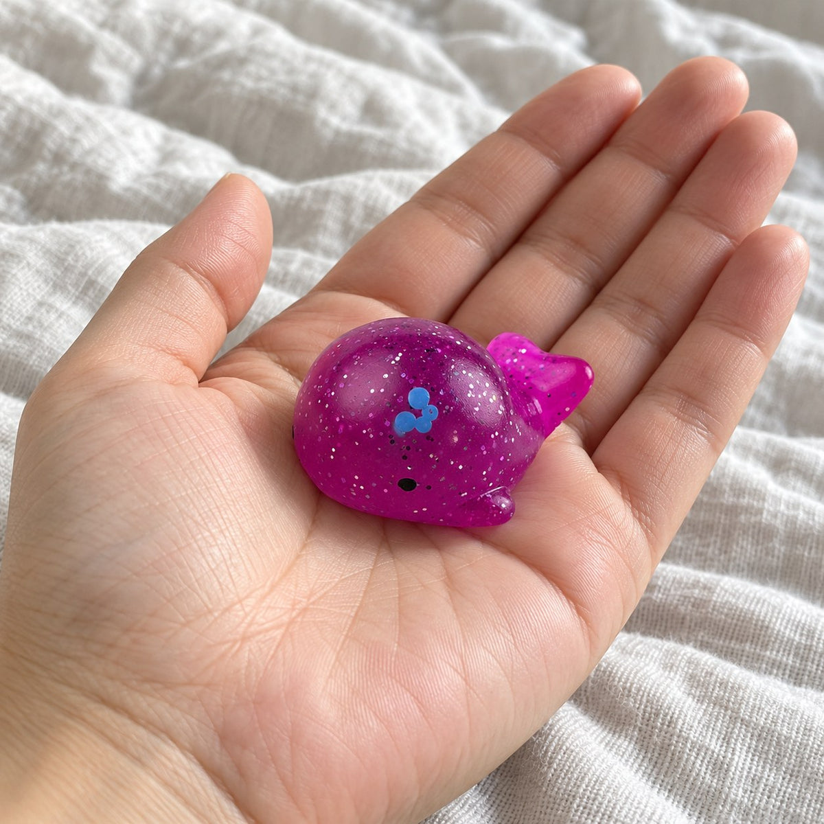 Mochi Squishy Whale with Glitter, held toward the camera, first-person view
