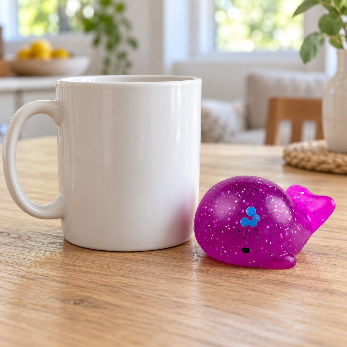 Mochi Squishy Whale with Glitter, next to a coffee mug for size comparison