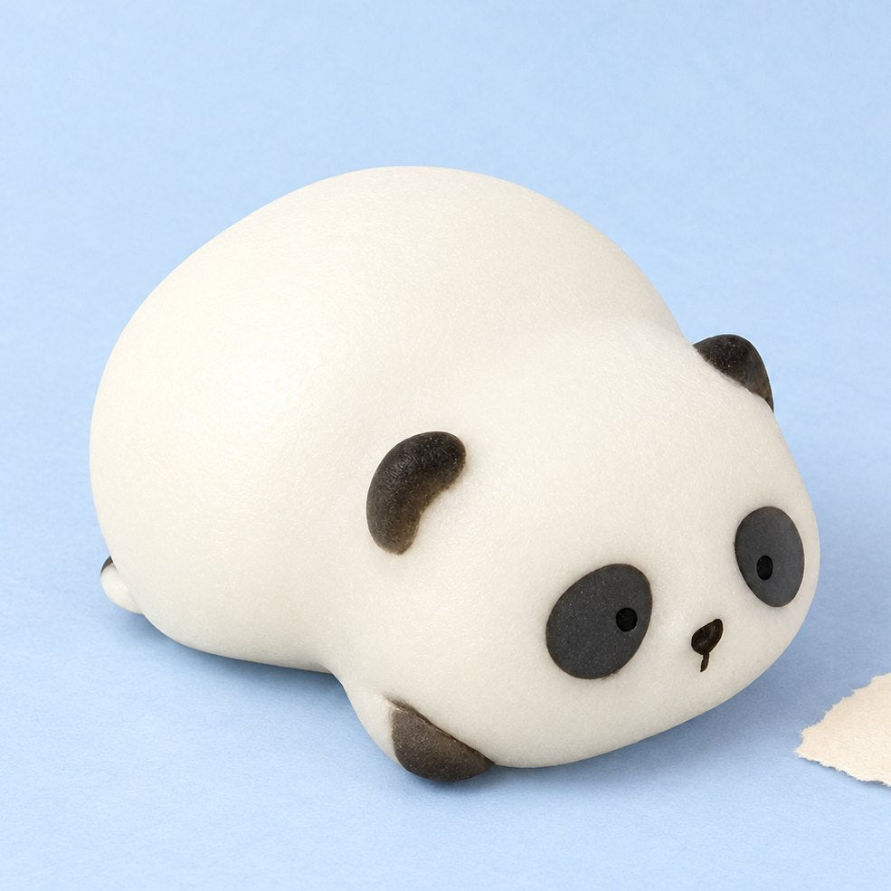 Panda squishy, liggende panda in een cadeaudoosje, op pastelkleurig papier