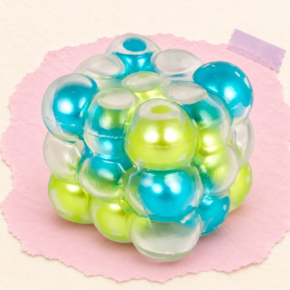 Blauwgroene parelkubus squishy met parelballetjes, 6 cm, op pastelkleurig papier