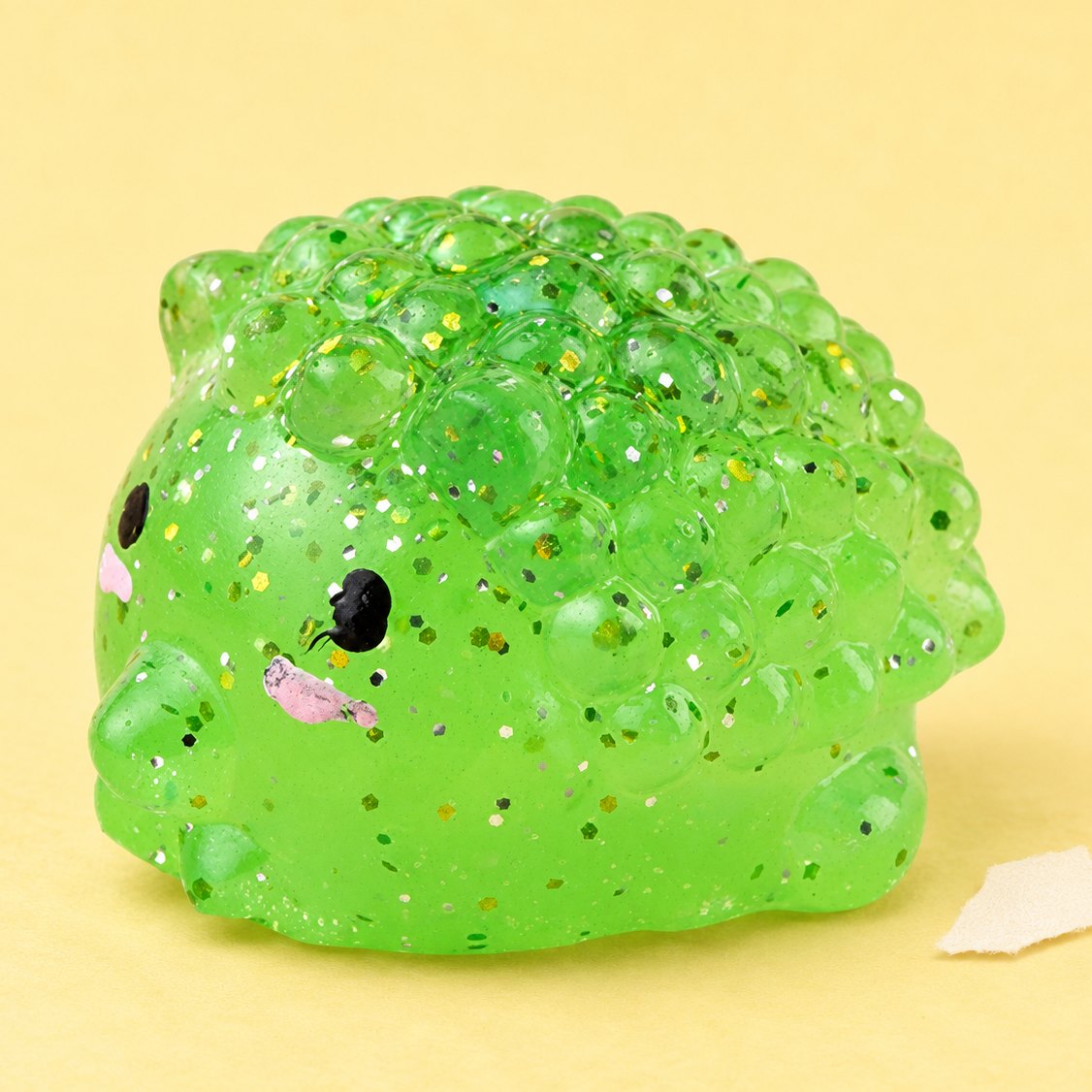 Pindsvin-squishy med glimmer, produktfoto på pastelfarvet papir