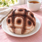 Pineapple bun squishy slow rising (12 cm, brown), on a plate on a breakfast table
