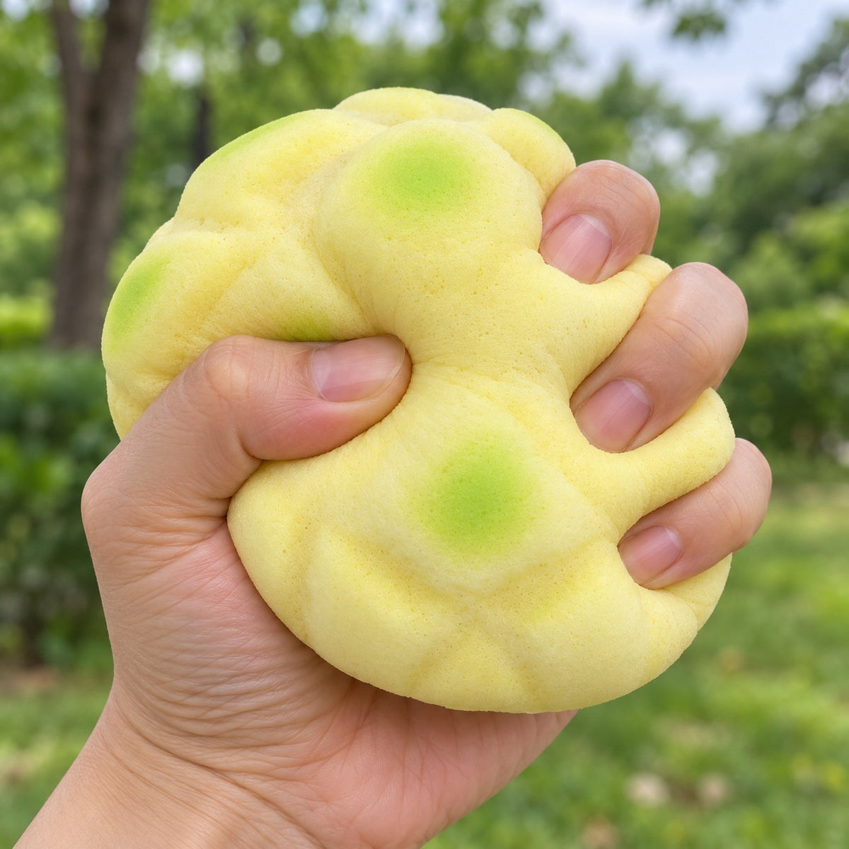 Pineapple bun squishy soft (12 cm, green), being squeezed by hand, soft and squishy