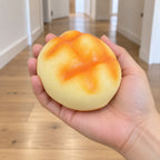 Pineapple bun squishy soft (8 cm, golden), held in a hand to show the real size