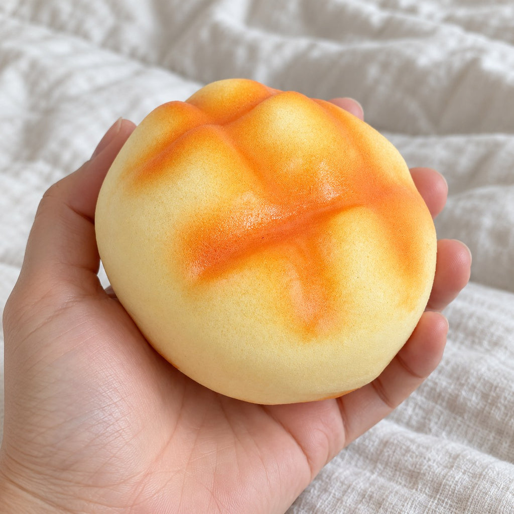 Pineapple bun squishy soft (8 cm, golden), held toward the camera, first-person view