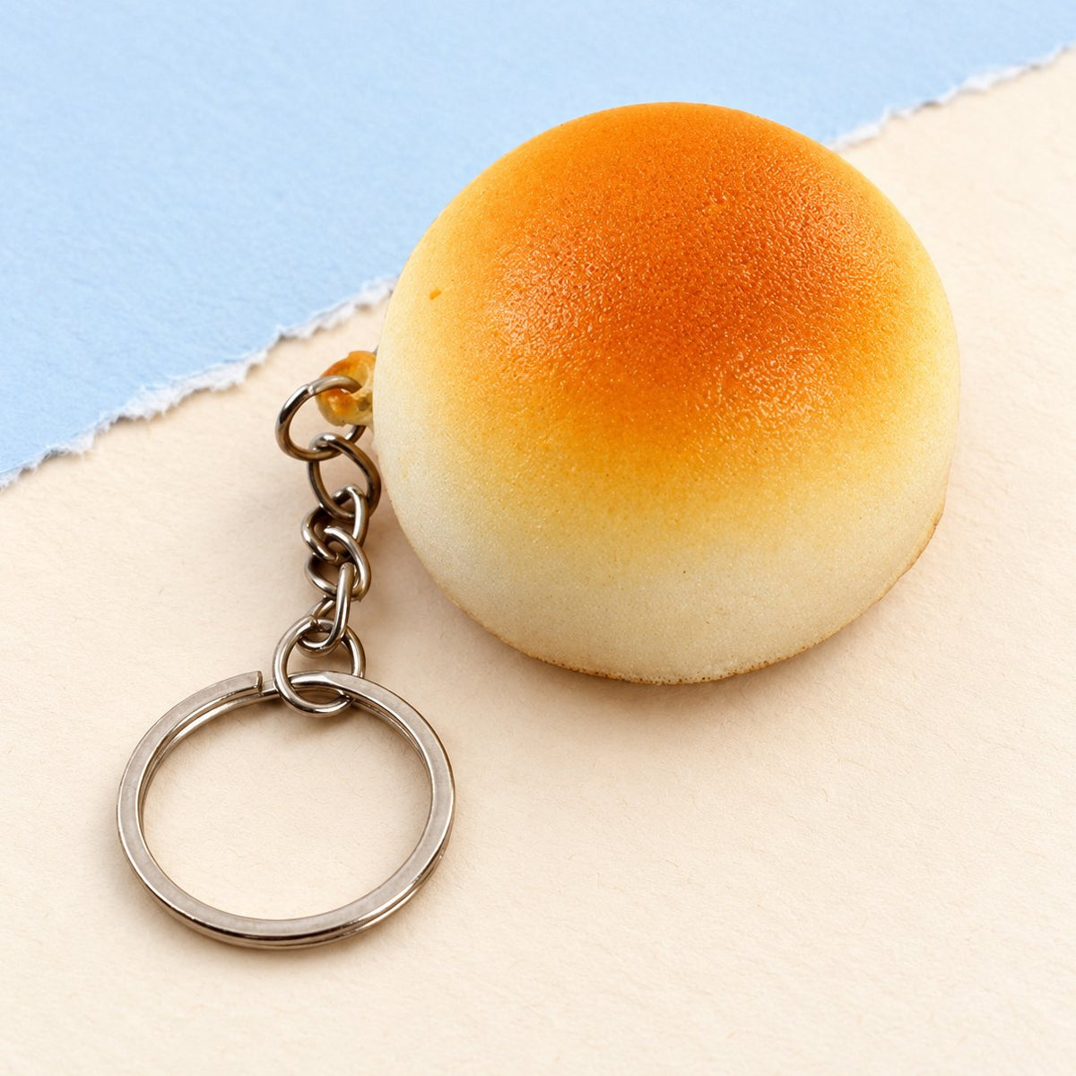 Portachiavi squishy panino dorato da 4 cm su carta pastello