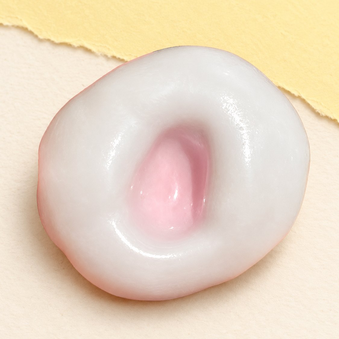 Mochi riskaka squishy, jordgubbsrosa med töjbart isskal, på pastellpapper
