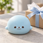 Seal Dumpling Squishy, Slow Rising PU (blue), as a small gift next to a wrapped box