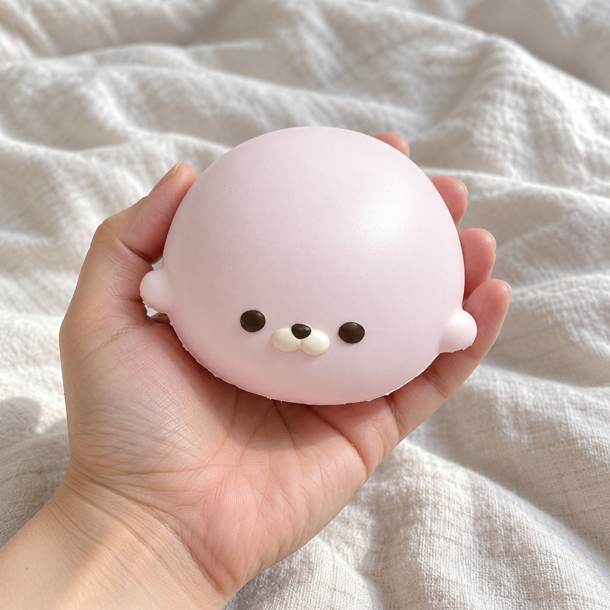Seal Dumpling Squishy, Slow Rising PU (pink), held toward the camera, first-person view