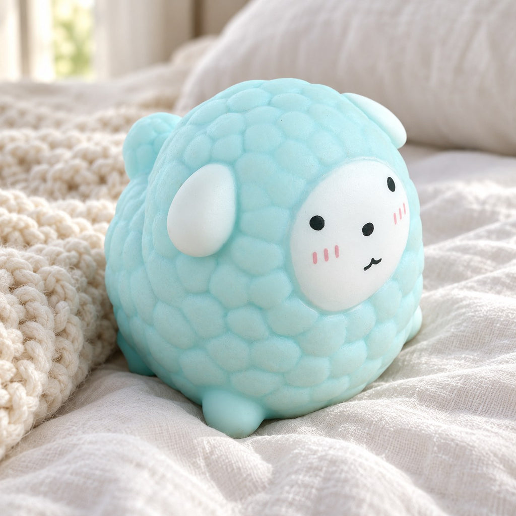 Sheep Squishy, Fluffy Lamb in Pastel TPR (blue), on a cozy bed with soft blankets