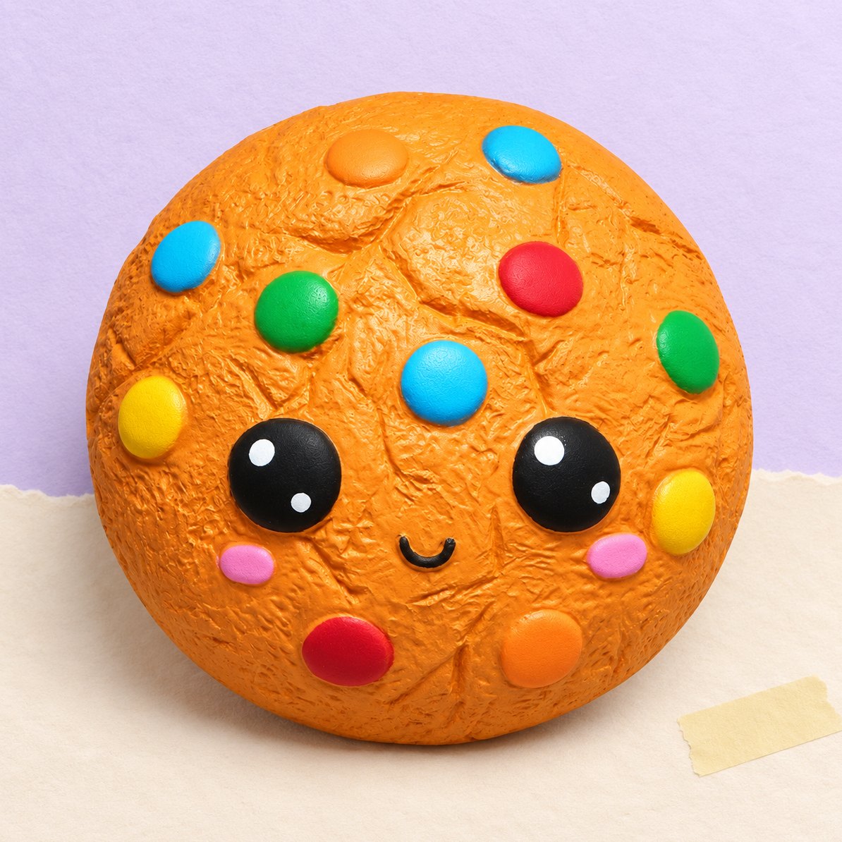 Slikkage-squishy, kawaii småkage med slik, produktfoto på pastelfarvet papir